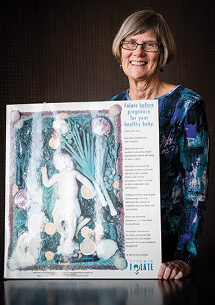 Professor Carol Bower with an early promotional poster for folate
